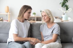 Loving adult daughter talking to sad old mother holding hand comforting upset older woman having problem, young caregiver helping senior patient, support, empathy and care to elderly parent concept