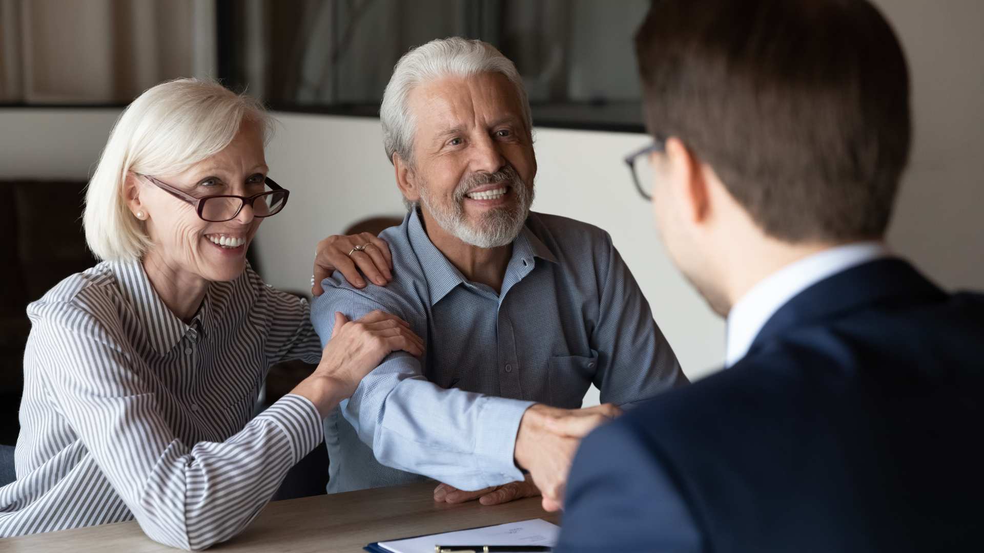 Older couple shaking hands with a man in a blue suit representing a strategy for cognitive decline in your estate planning.